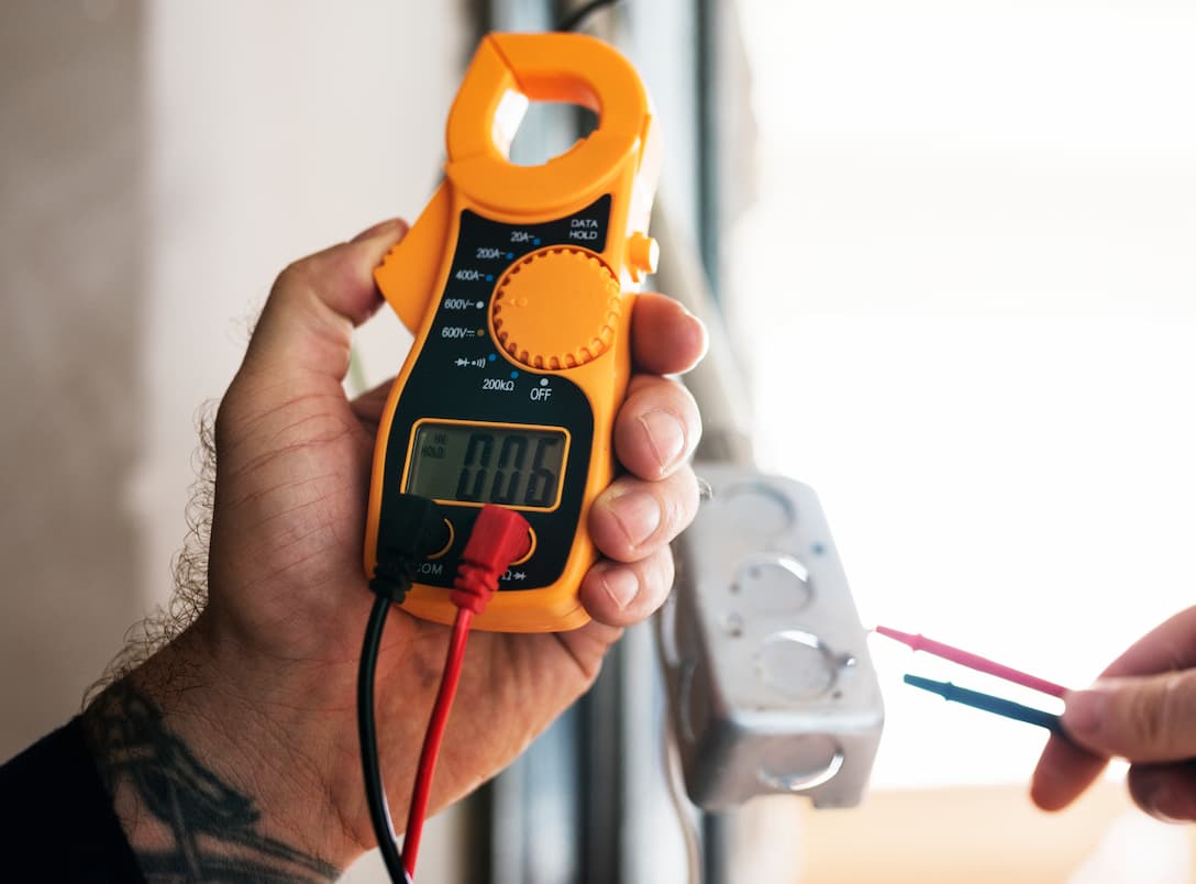 Electrician using a voltage tester on a wall socket during fault finding